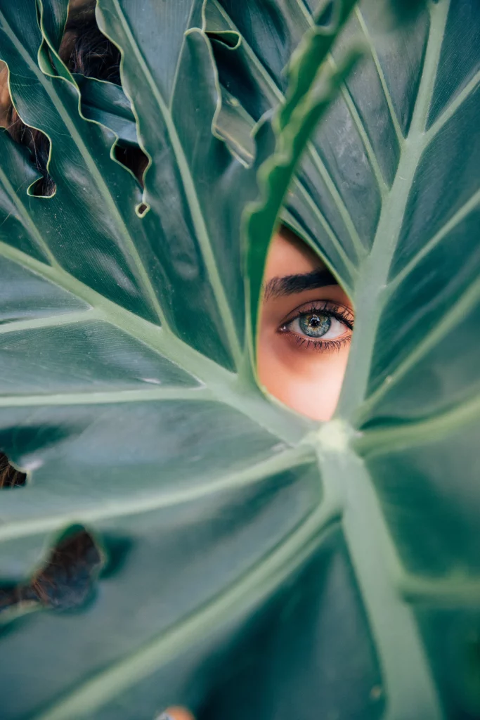 Myers_-Cocktail A woman looking at the camera with her face obscured by some leaves
